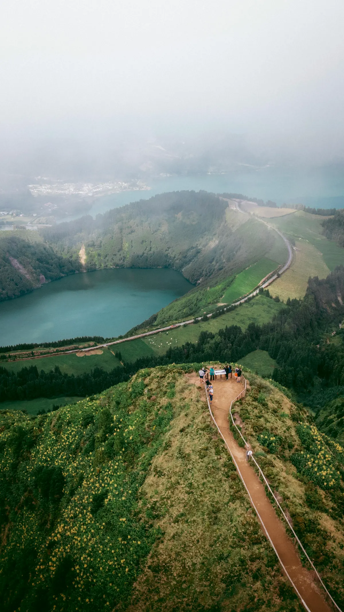 A ridge trail above a crater lake in morning mist